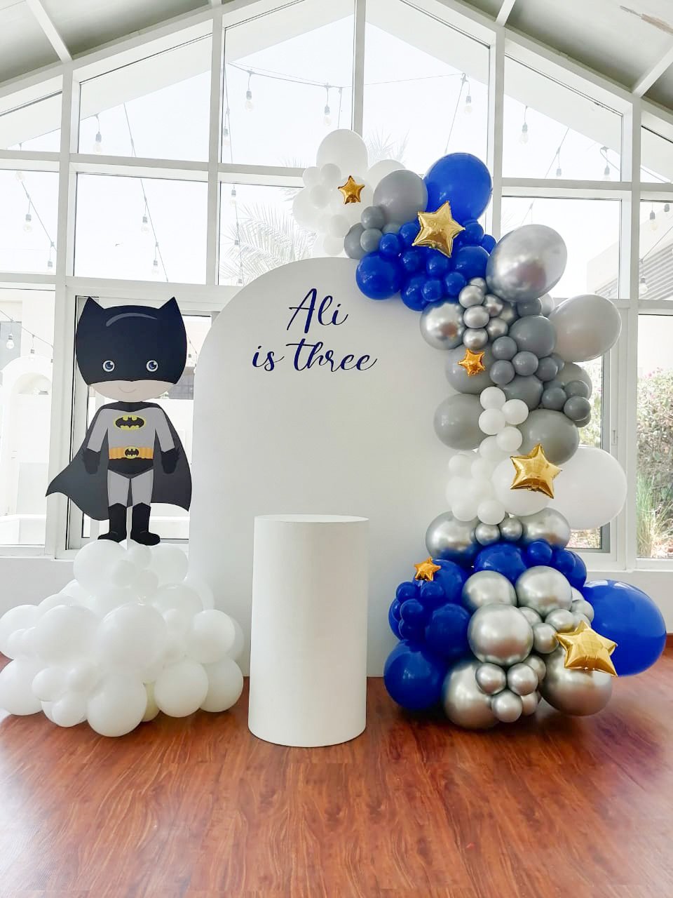 Baby Batman (1.8m semi arch backdrop 1x medium round plinth   text - Ali is Three (dark blue) Balloon garland with touches of star foil balloons)