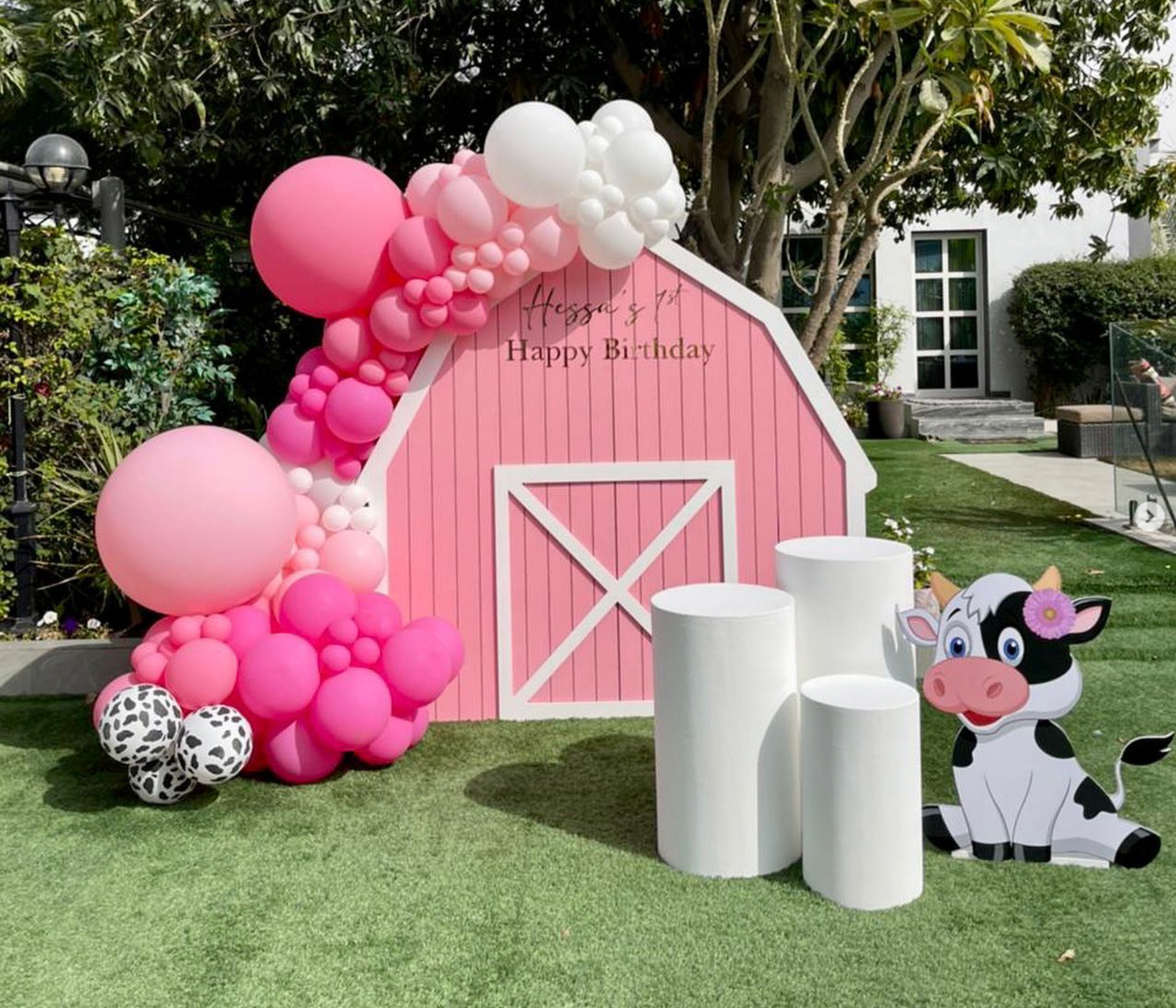 Pink barn house (Barn House backdrop 2m high- pink and white Personalization on backdrop Balloon garland 3 x white circle tables 1 x cow foam board (1m height))
